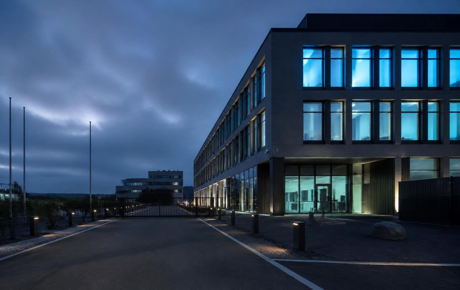 Secure corporate operations building with gated entrance at dusk