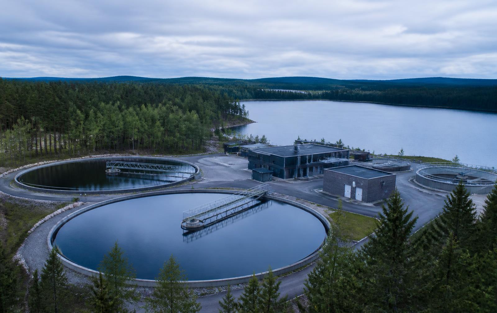 Water treatment works with circular basins beside a forest reservoir
