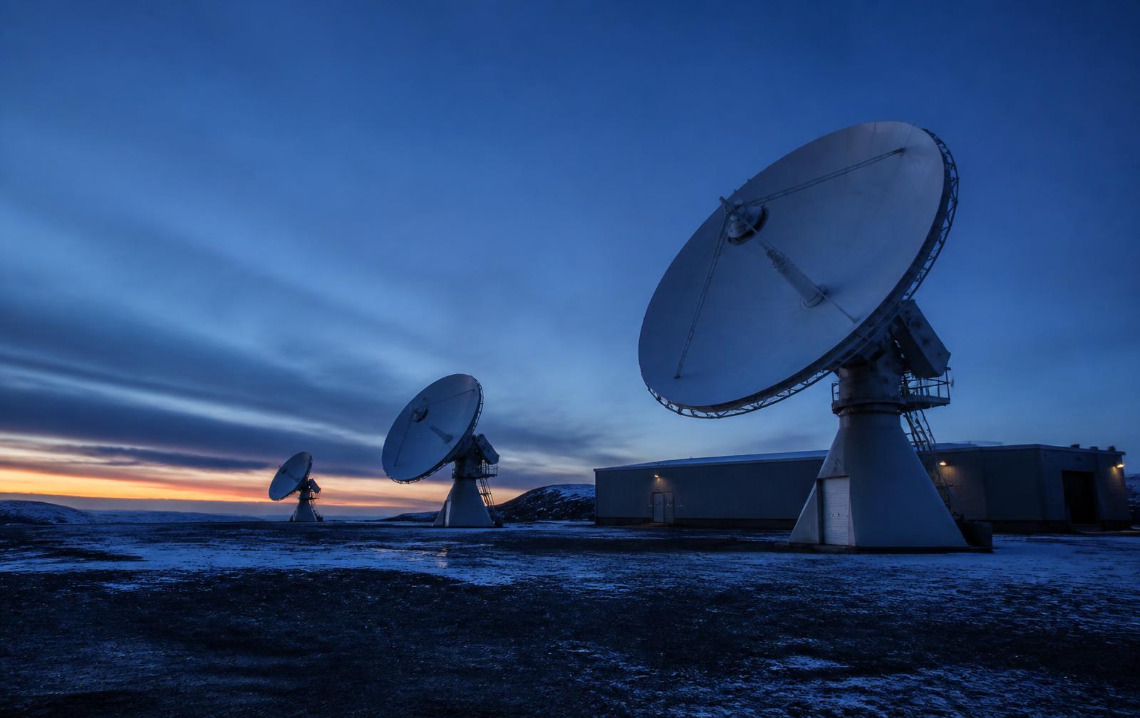 Satellite ground station with large parabolic antennas at twilight